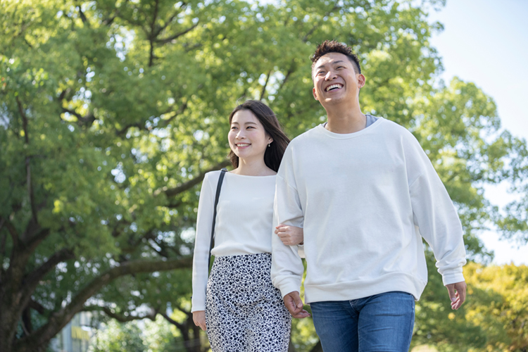 綺麗な緑を背景に仲良く歩く若い男女 
