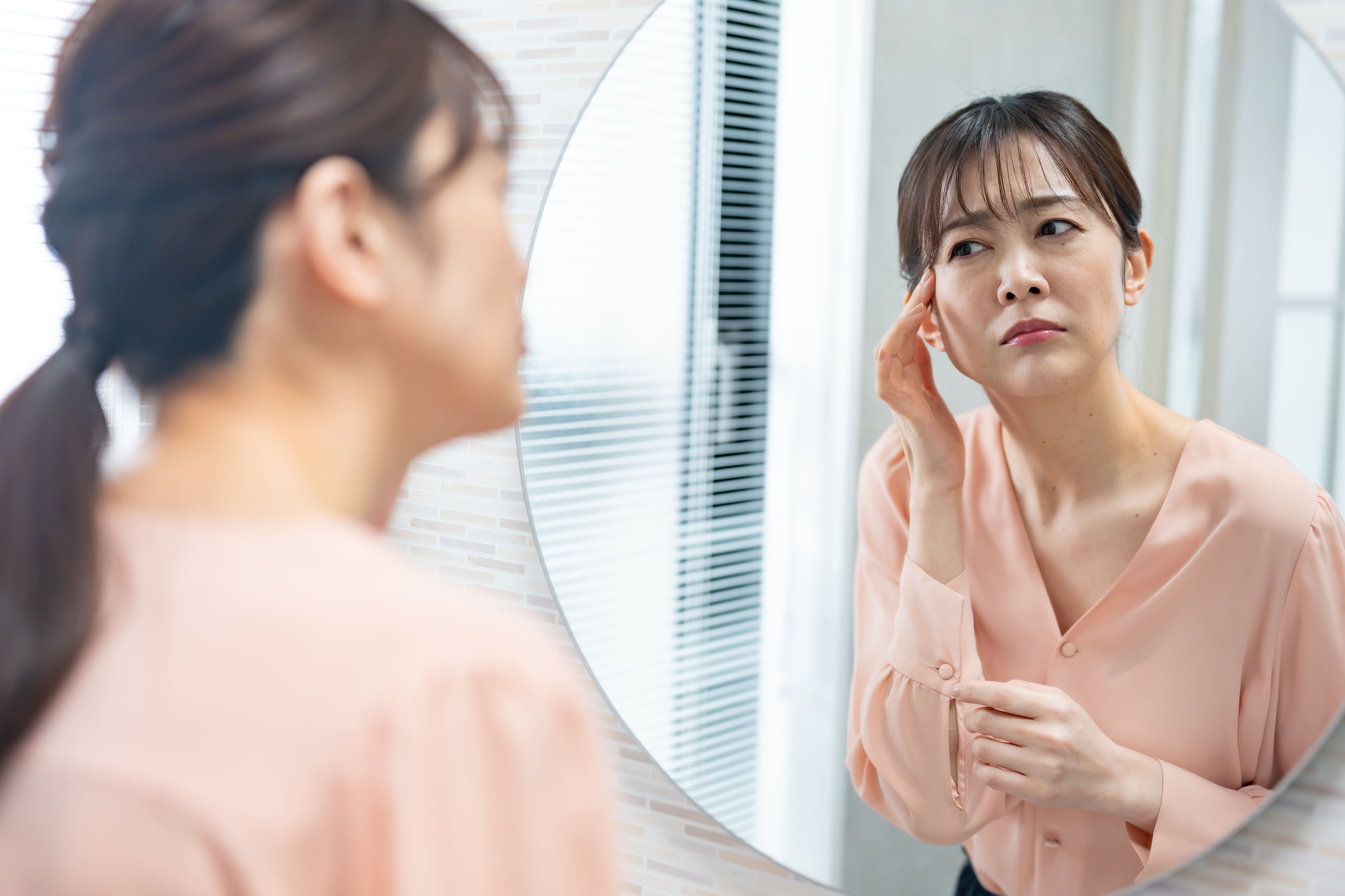鏡を見ながら目元の状態を気にする女性