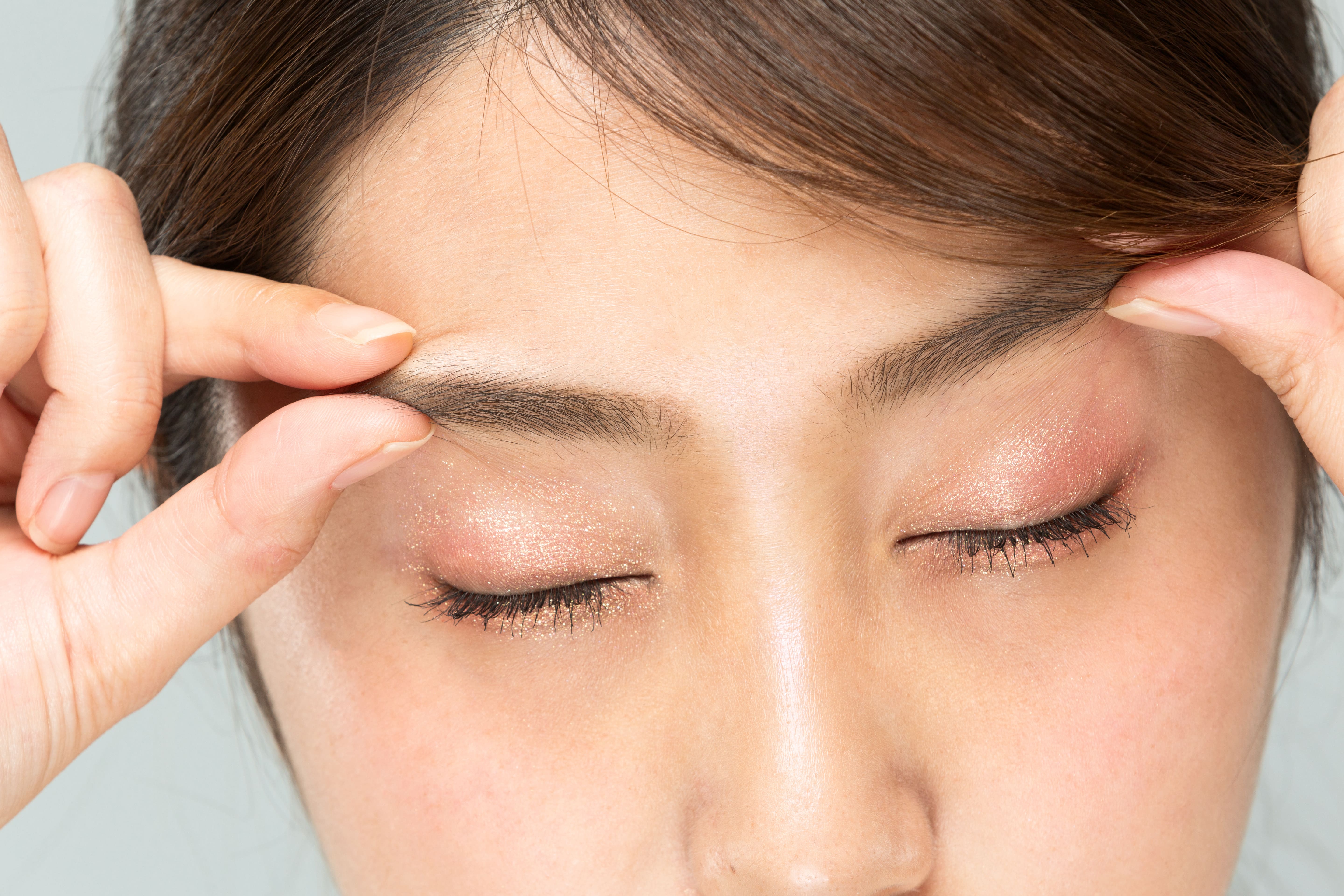 眉毛の形を指で整える女性のクローズアップ
