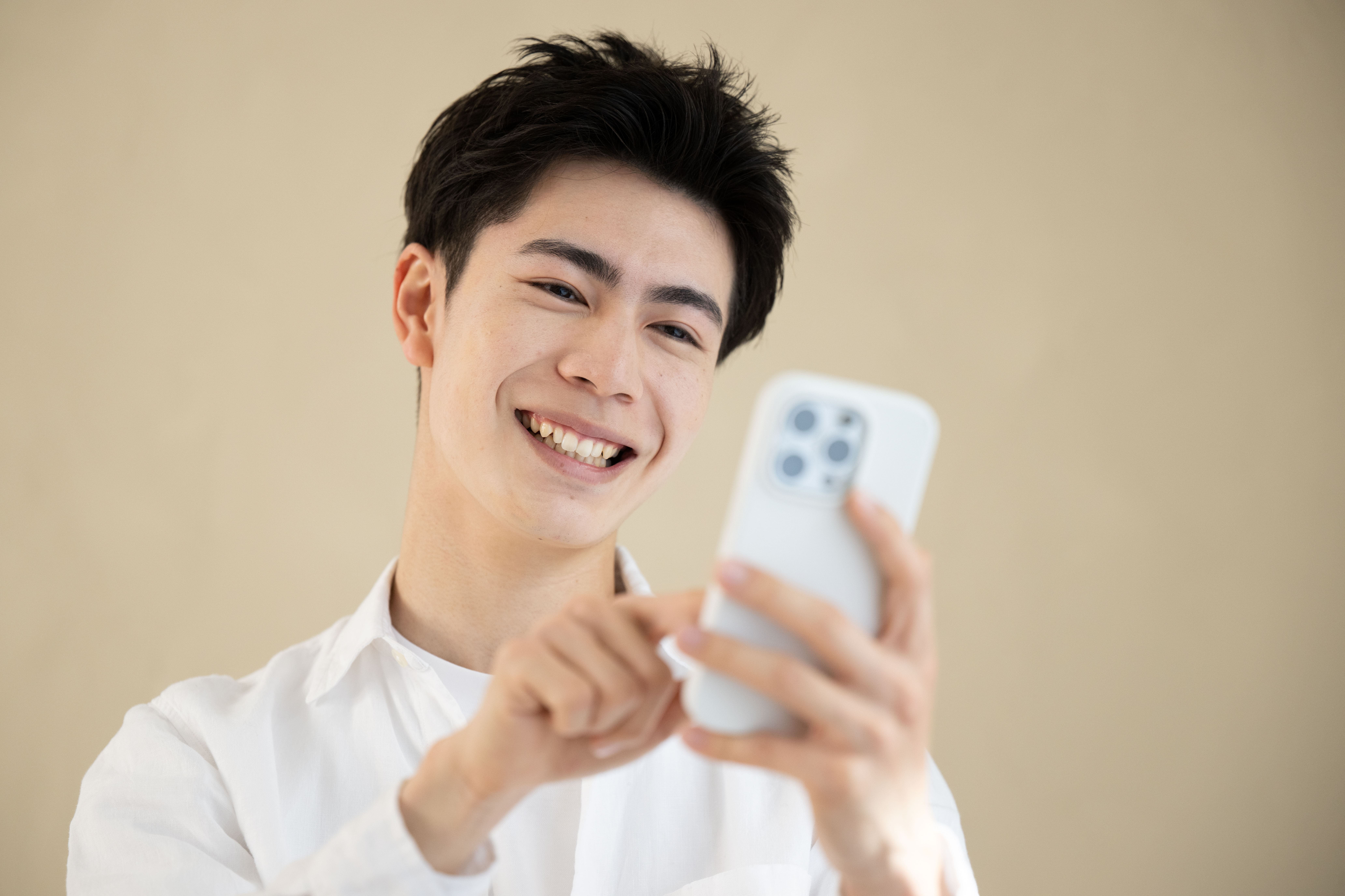 スマートフォンを操作しながら笑顔の男性