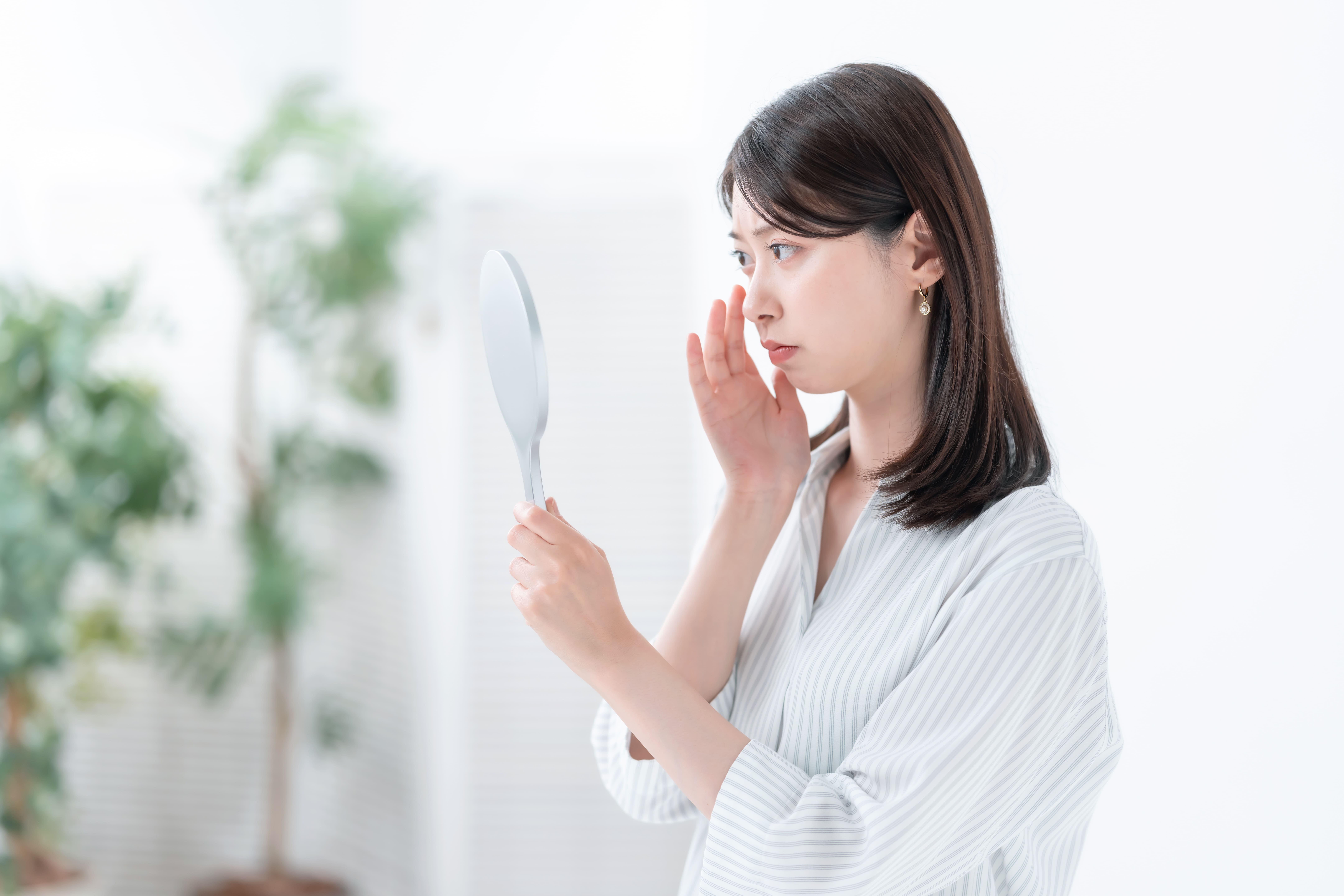 鏡を見ながら眉毛の状態を気にする女性