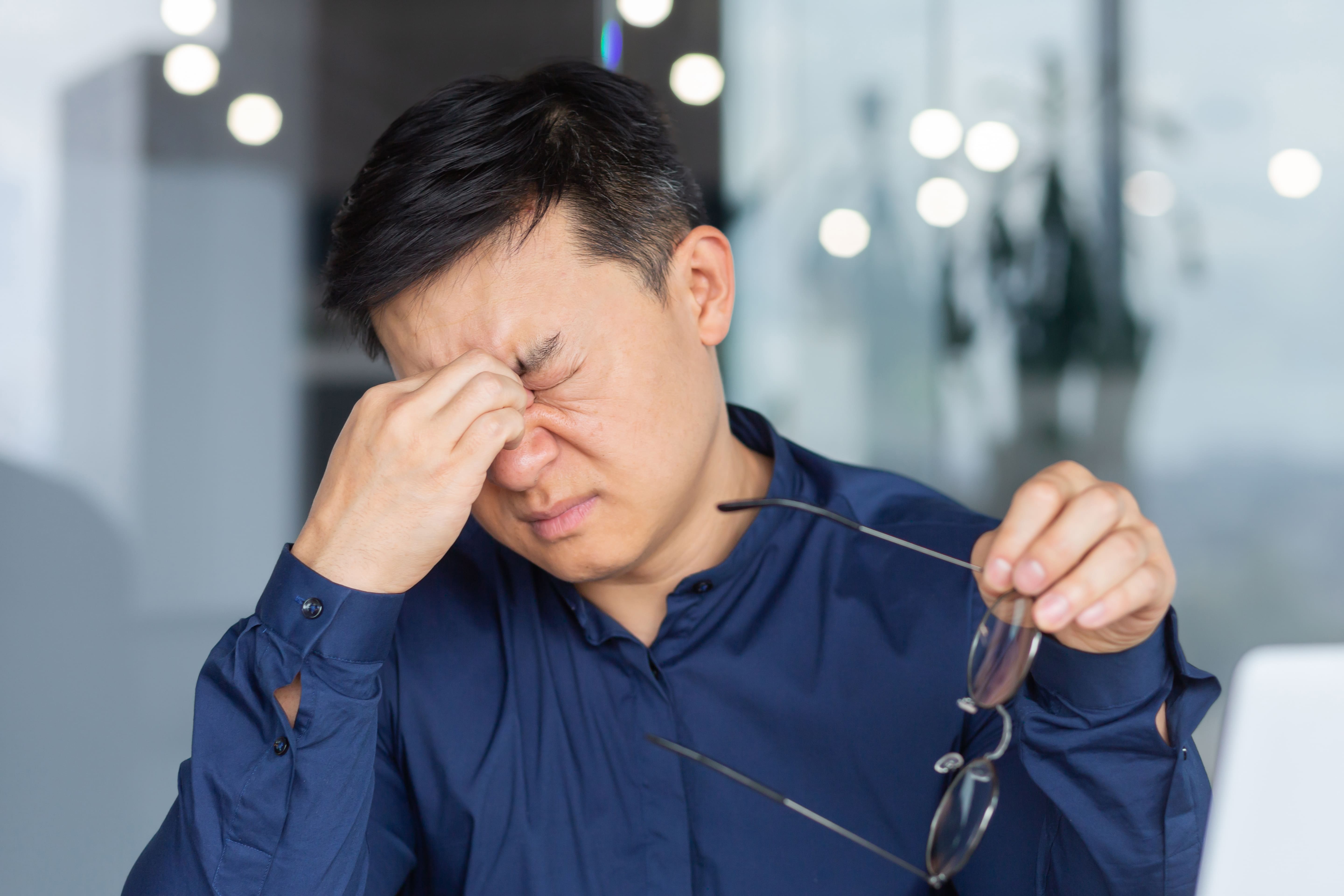 目元に違和感を感じて目を押さえる男性